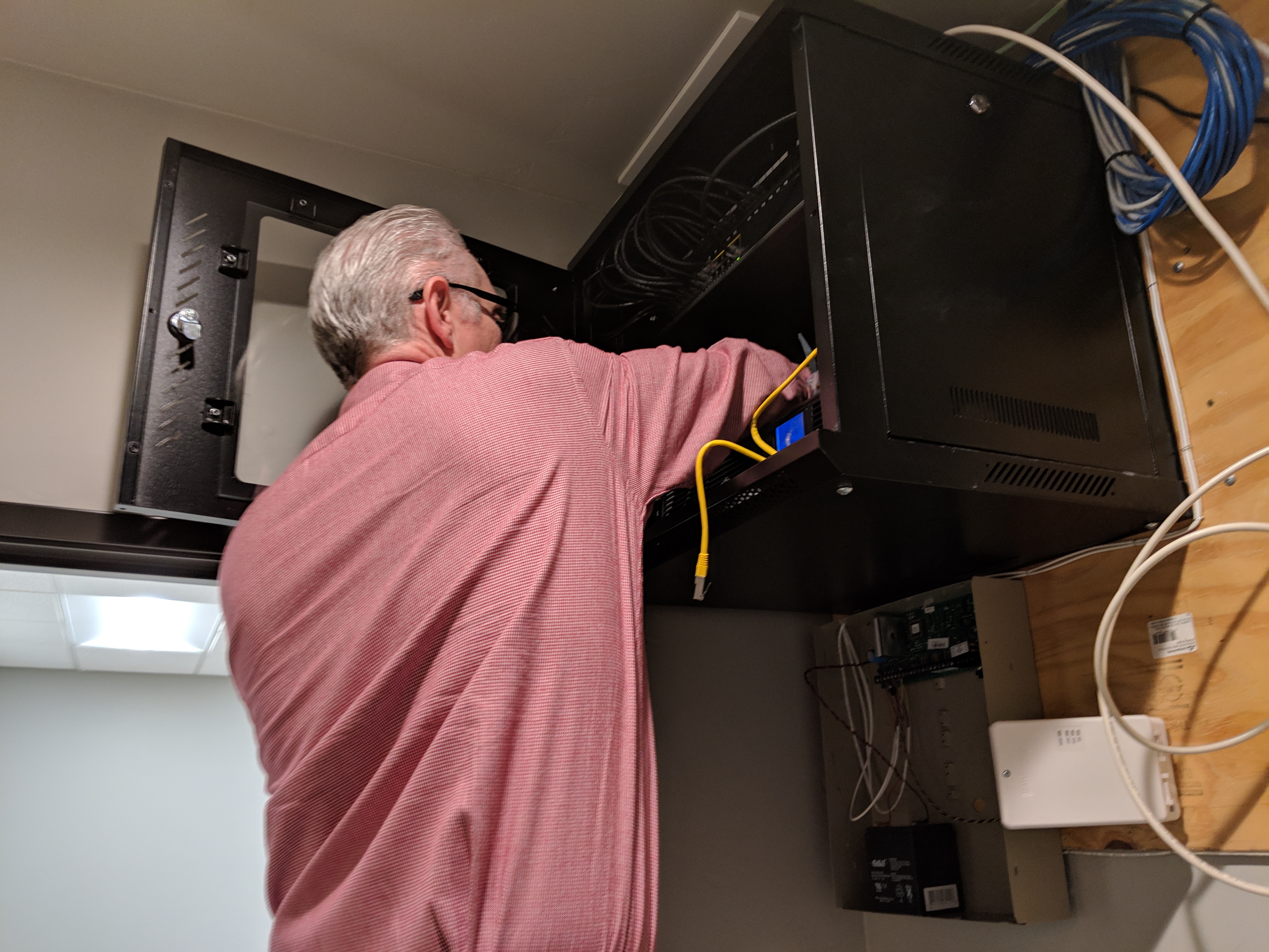 Man reaching into a case full of tech hardware. 